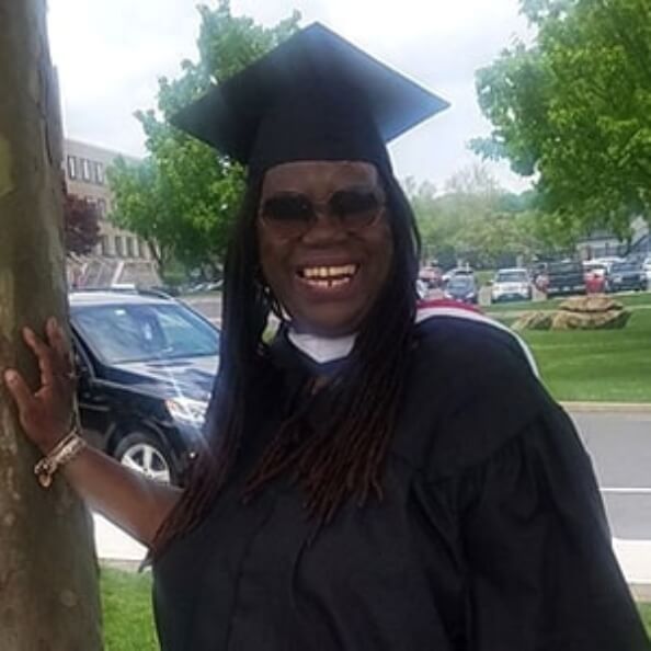 Coreen Martin smiles while wearing a cap and gown outdoors.