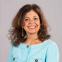 Patricia Pivarnik smiles in front of a gray background