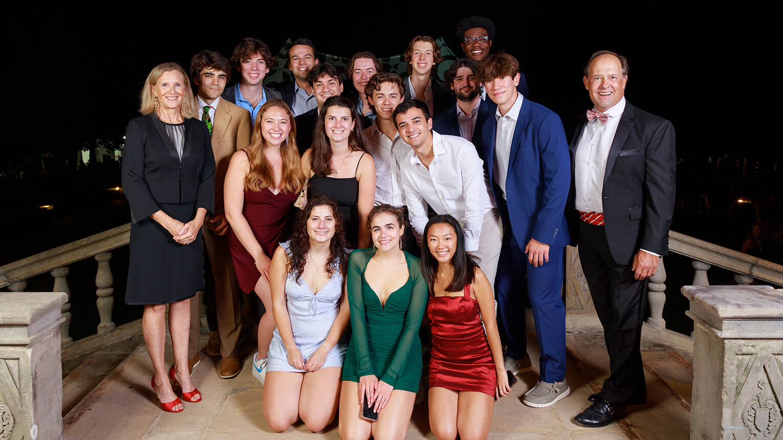 A diverse group of individuals smiling and posing together at night, capturing a joyful moment in a photograph.  