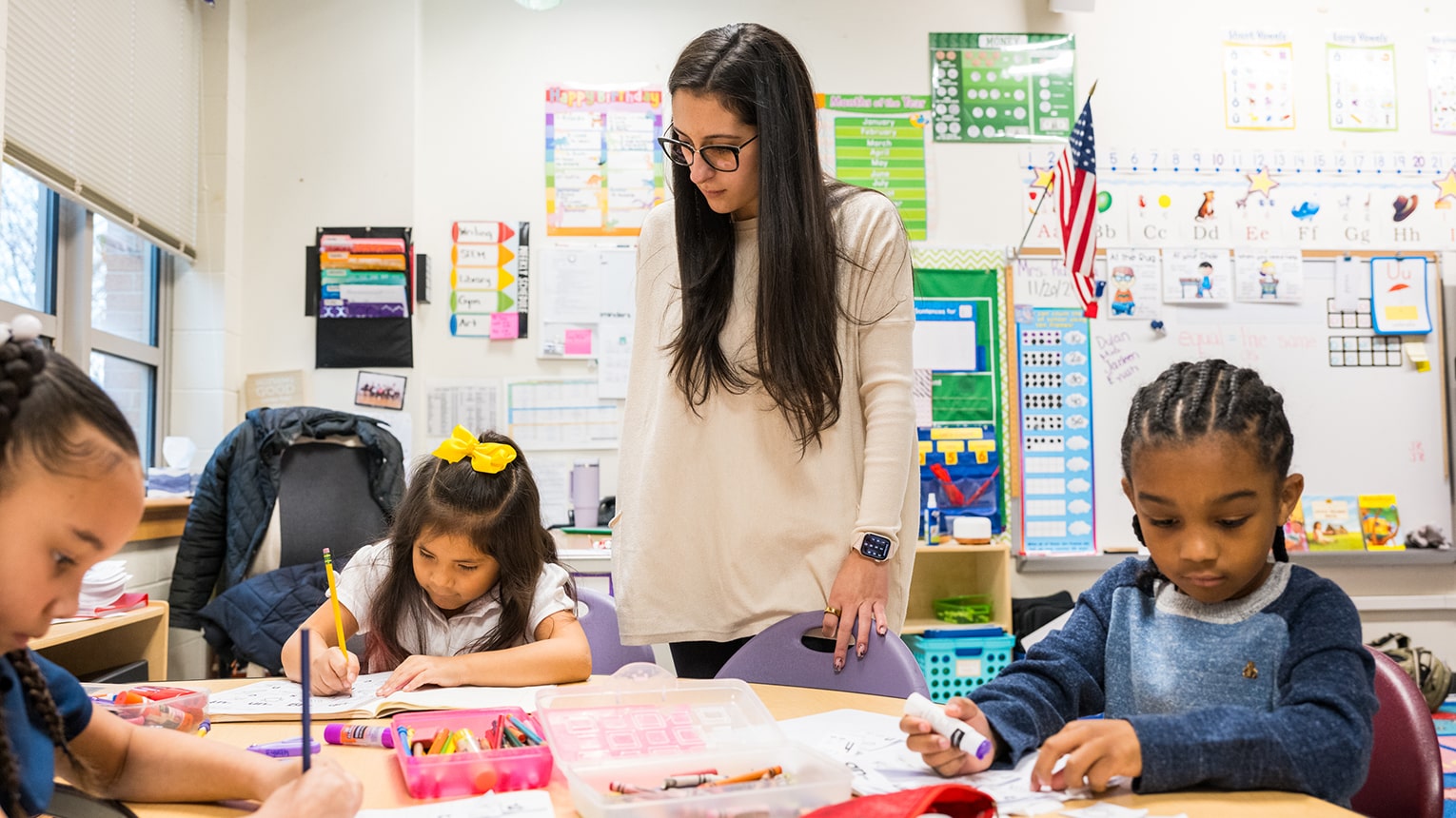 A female SEHD graduate candidate supervising children as they color and draw.