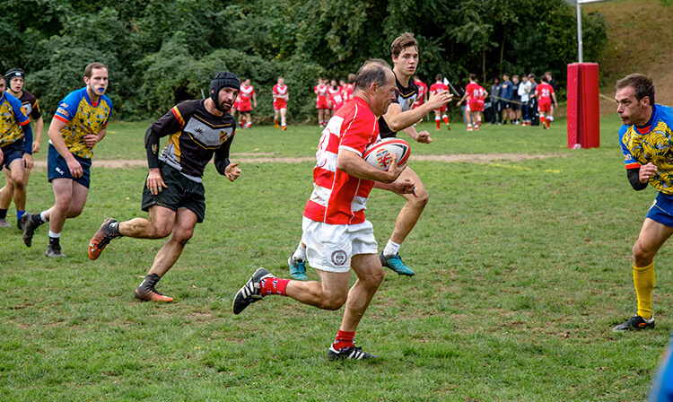 A group of men engaged in an intense rugby match on a grassy field, showcasing teamwork.