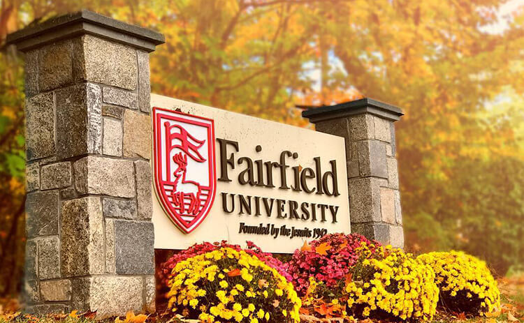 The Fairfield University sign, clearly visible, serves as a welcoming landmark at the entrance of the campus.