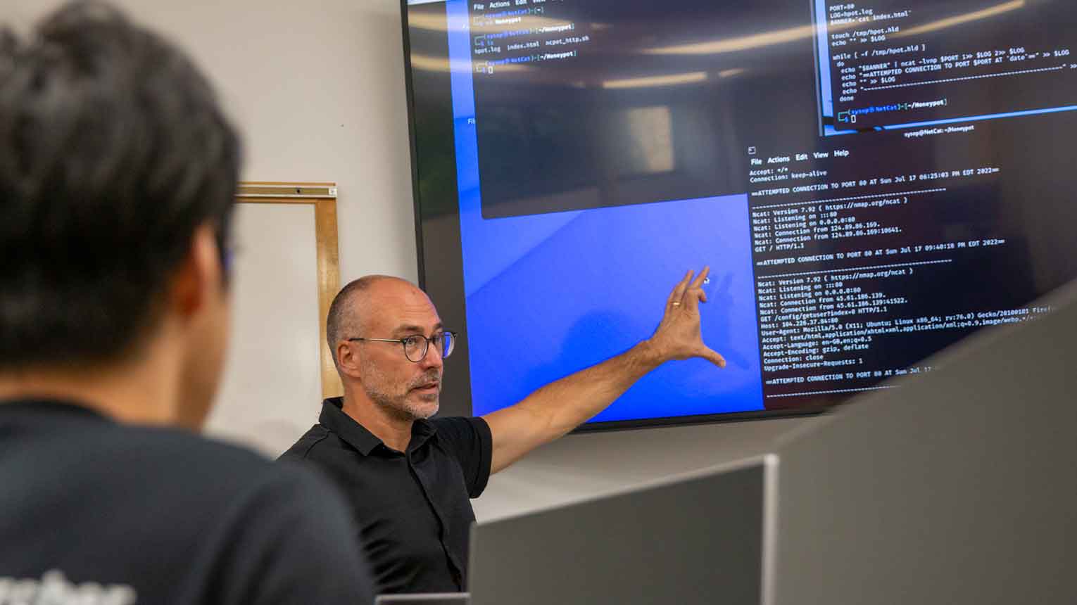 A professor teaches a course in the Cybersecurity lab. 