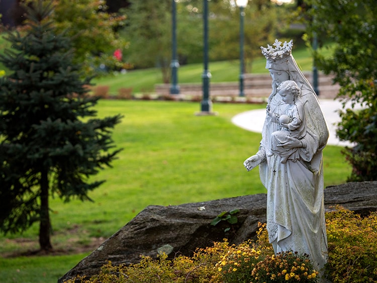 Statue of Mary with the Baby Jesus in a garden located on Fairfield University's campus.