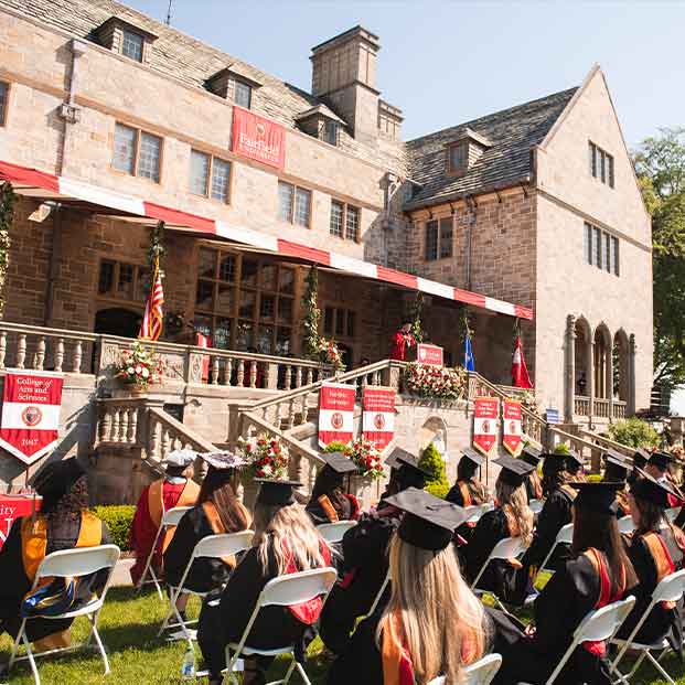 A group of graduates in chairs outside a building, celebrating their achievements together.