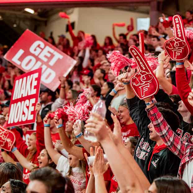 Student cheering and waving signs at and athletic event