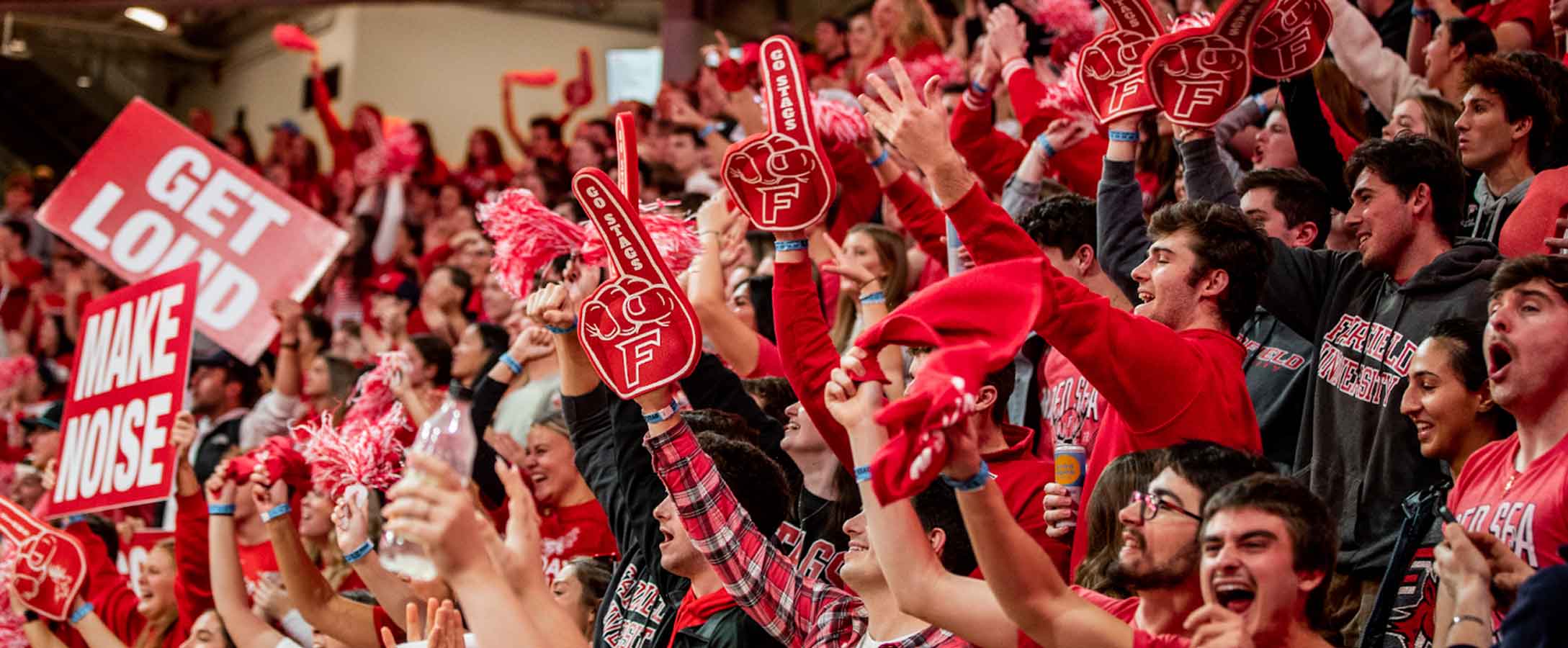 Student cheering and waving signs at and athletic event