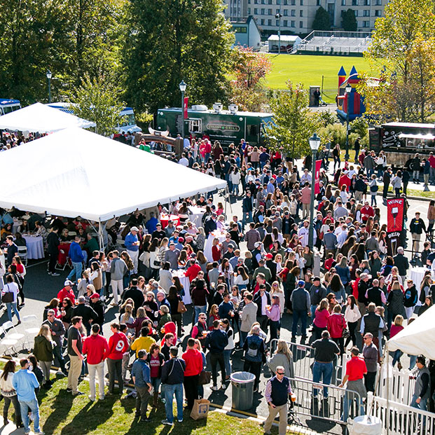 A large crowd gathers at an outdoor event, enjoying the atmosphere and activities around them.