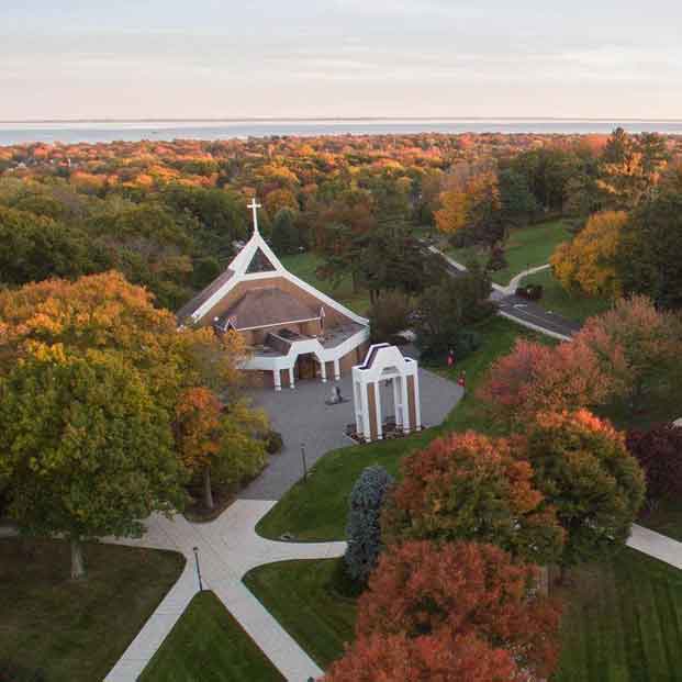 Aerial photo of ϲʹ campus with Egan Chapel surrounded by trees and the Long Island sound in the distance.