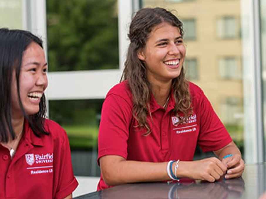 Students wearing red Fairfield collared shirts smiling. 