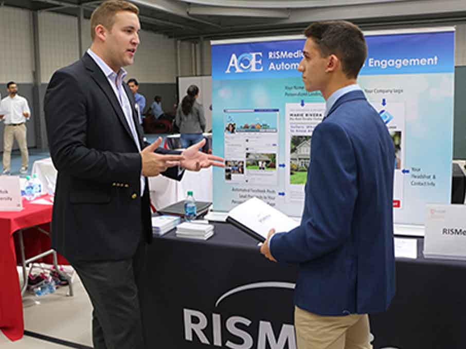 Student talking to a man in a suit at the career development week event. 