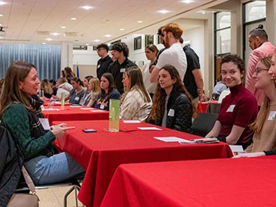 Student speaking to a panel of women at Alumni Career Night. 