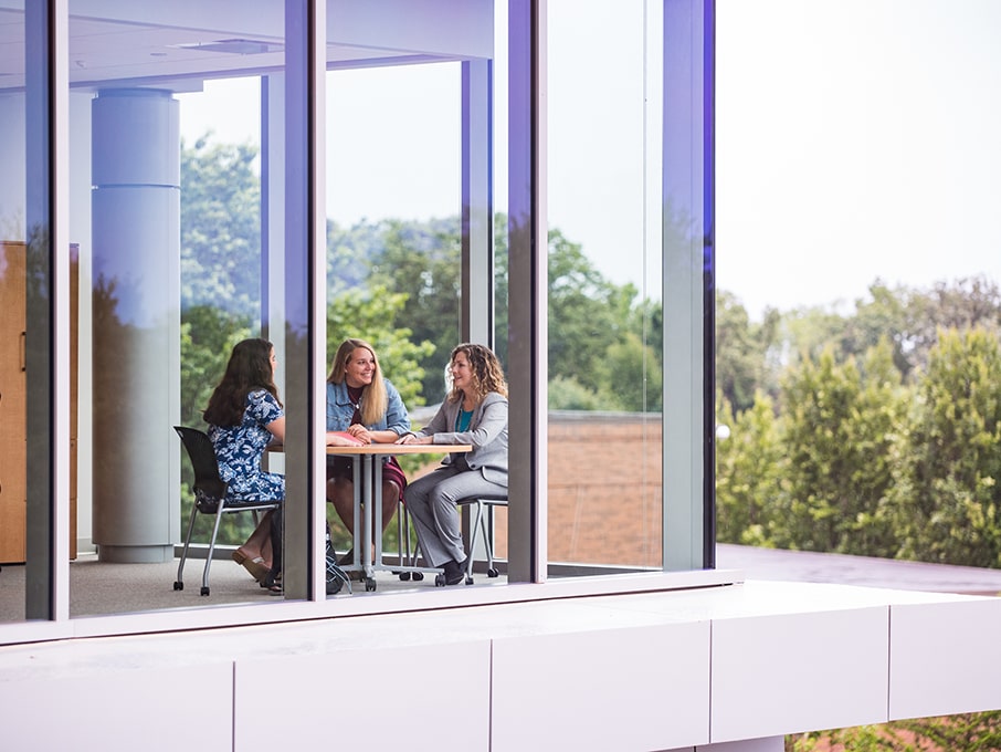 Shot from outside of students sitting inside of one of Fairfield’s buildings collaborating on something.