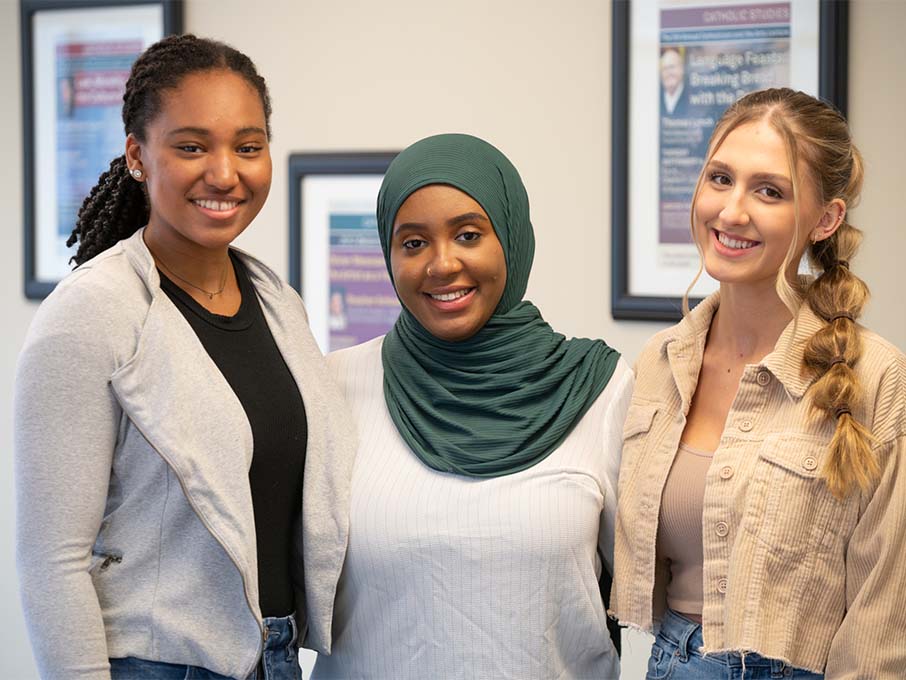 Three students smiling and posing for a photo. 