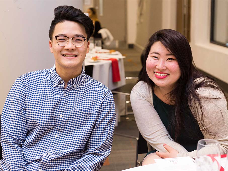 Two students wearing business casual attire smiling and posing for a photo at an event.