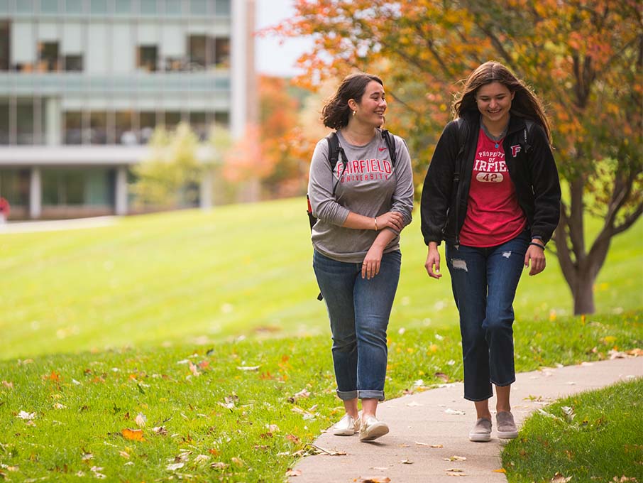 Three students walking next to a building on campus. 