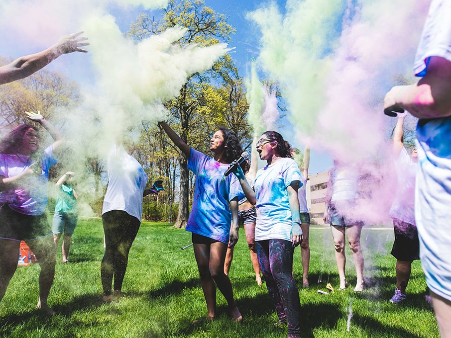 Students throw different colors of powder in the air.