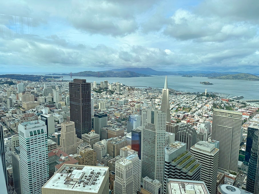 San Francisco skyline viewed from the top of a tower, showcasing iconic buildings against a clear blue sky.