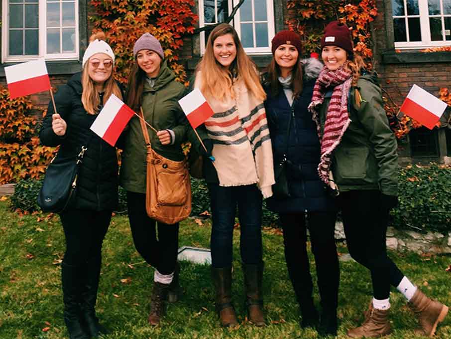 Students from Galway study abroad holding flags.