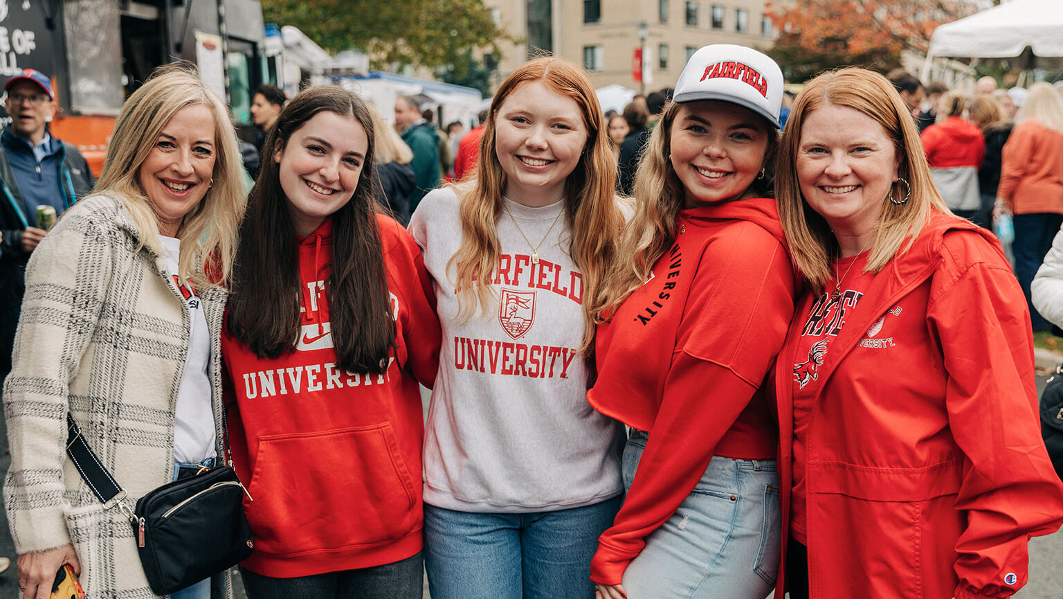 Five women dressed in red ϲʹ shirts and hoodies standing together, smiling for a photo.