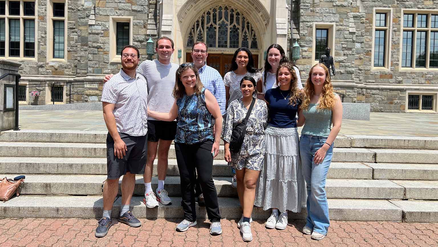 Students and professors standing outside in front of stone building