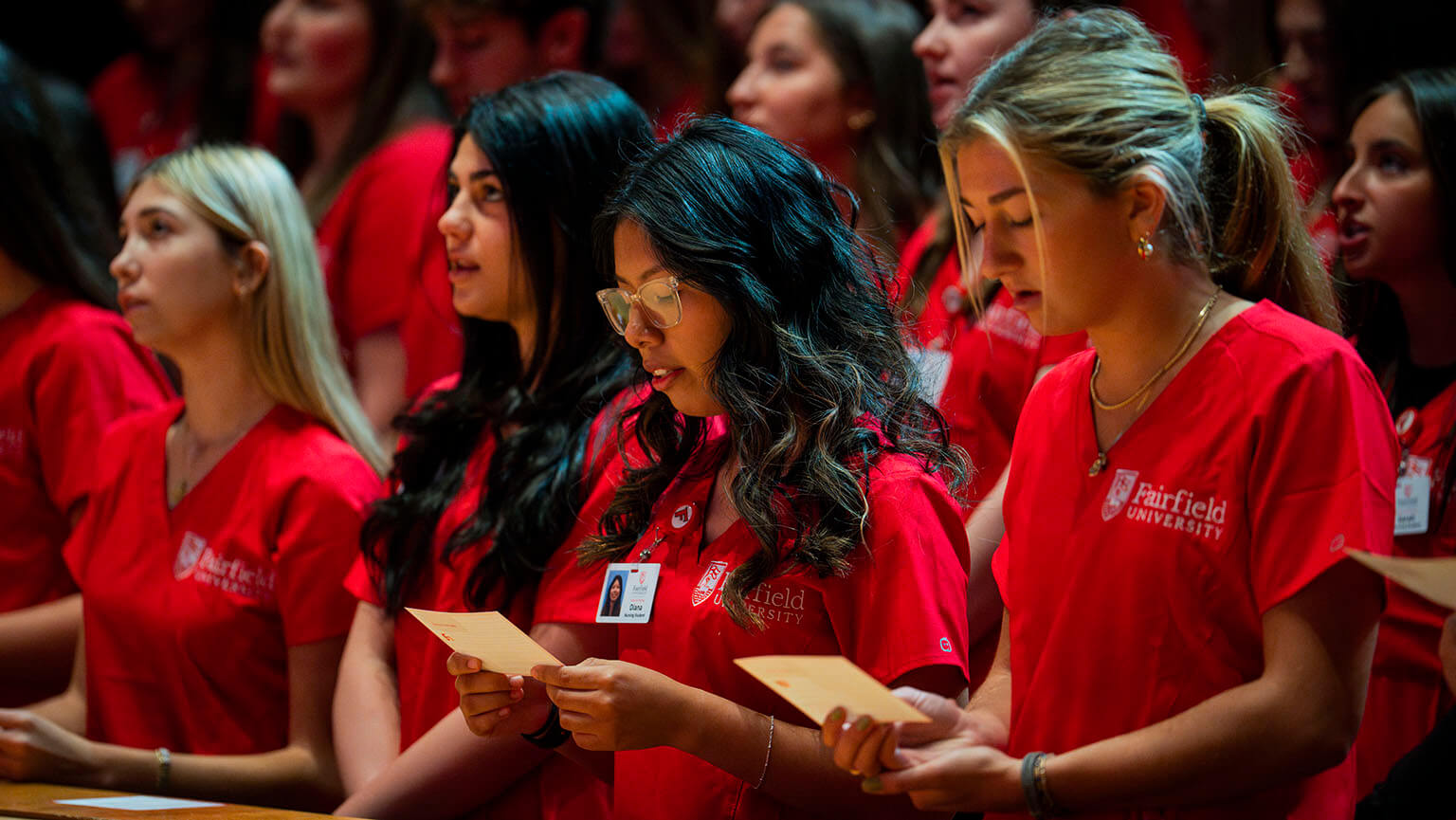 Nursing students in Fairfield-red scrubs at their clinical initiation ceremony, reciting their new code of conduct as a cohort.