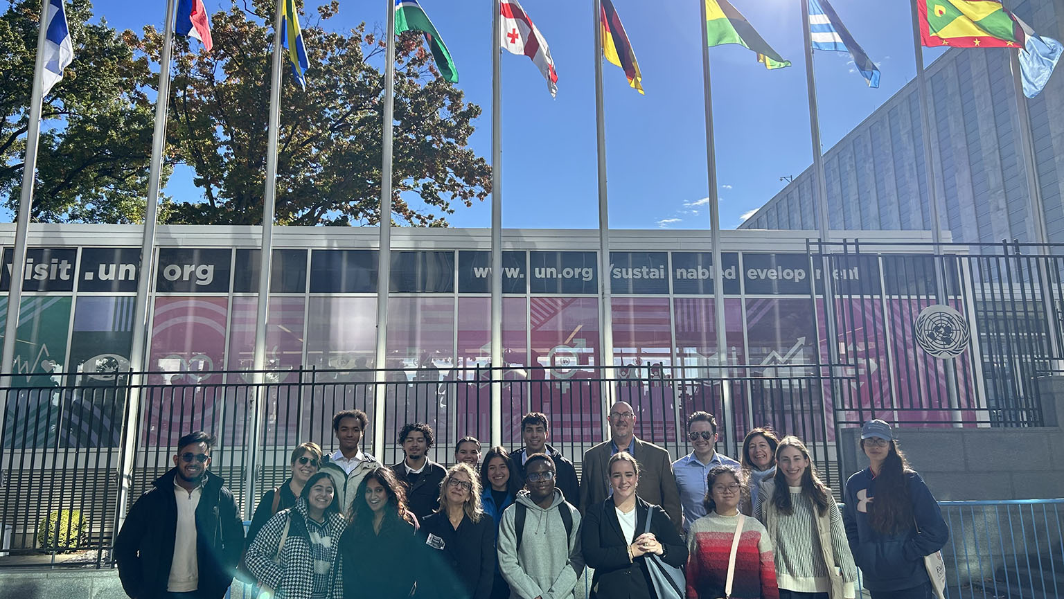 Students and faculty smiling for a group shot outside the United Nations headquarters building.