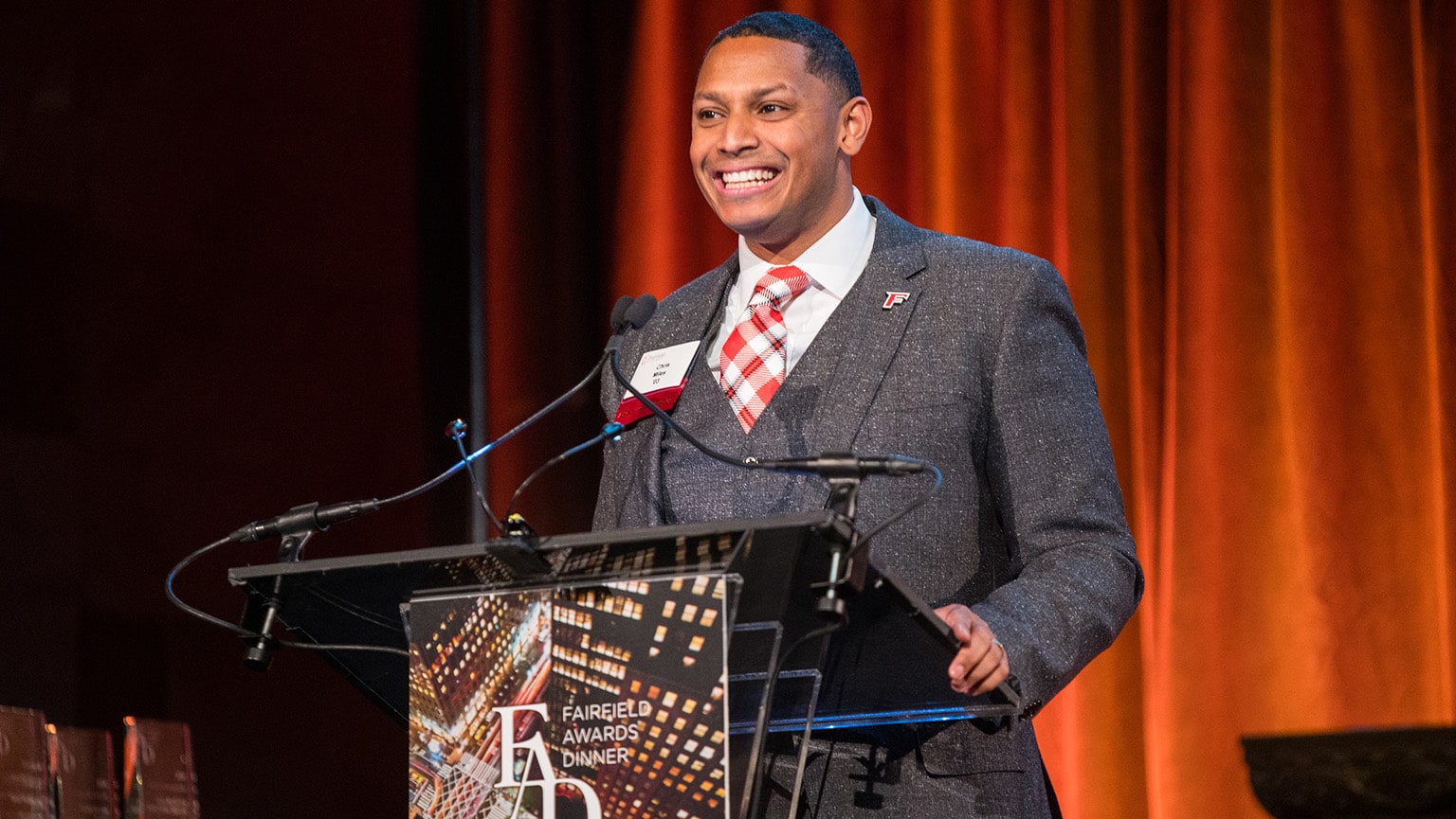 Emcee Chris Miles ’03 giving his Awards Dinner opening speech and remarks at a branded, on-stage podium.