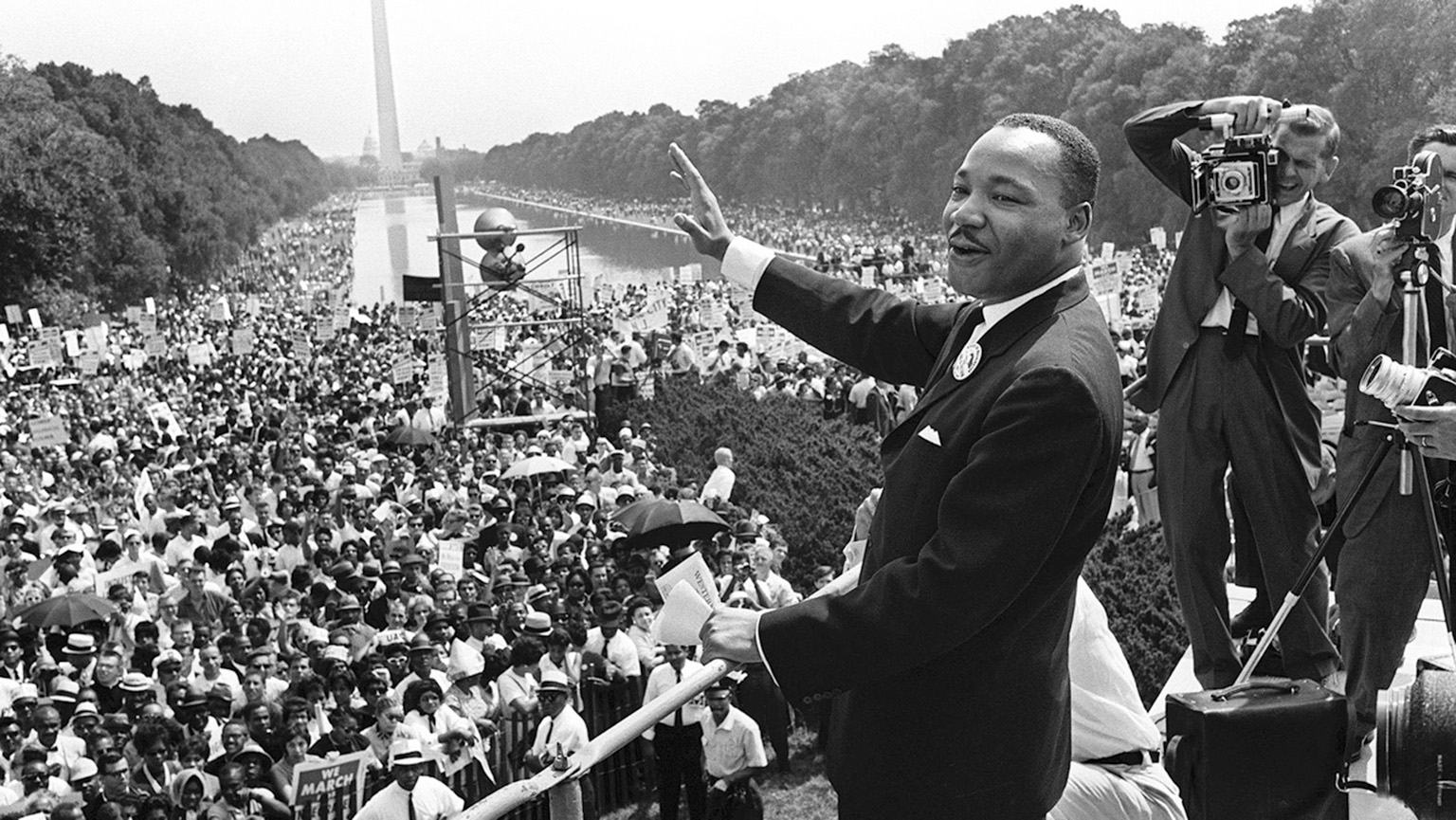 Historical, archival photo of Martin Luther King Jr. waving to the crowd before his speech.