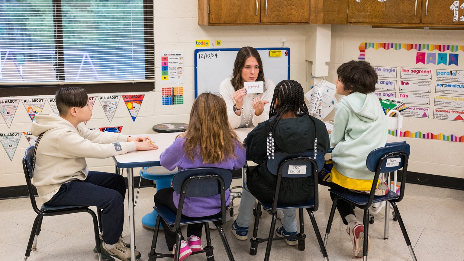 Fairfield student engaging with a small group of young, student children in a reading exercise.