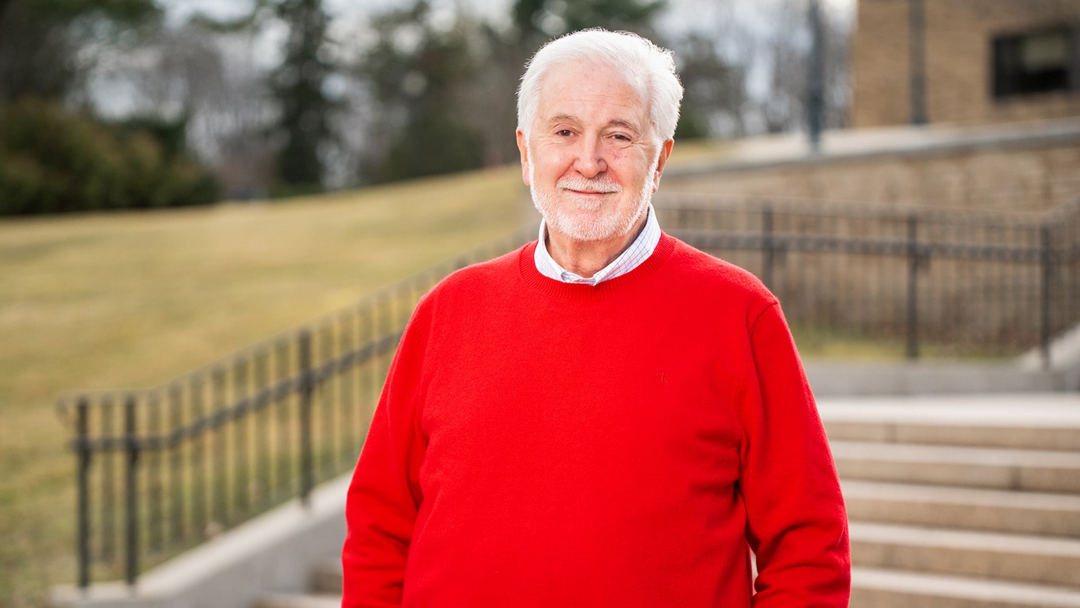 John Charles Meditz '70 dressed in a red sweater for his headshot portrait.