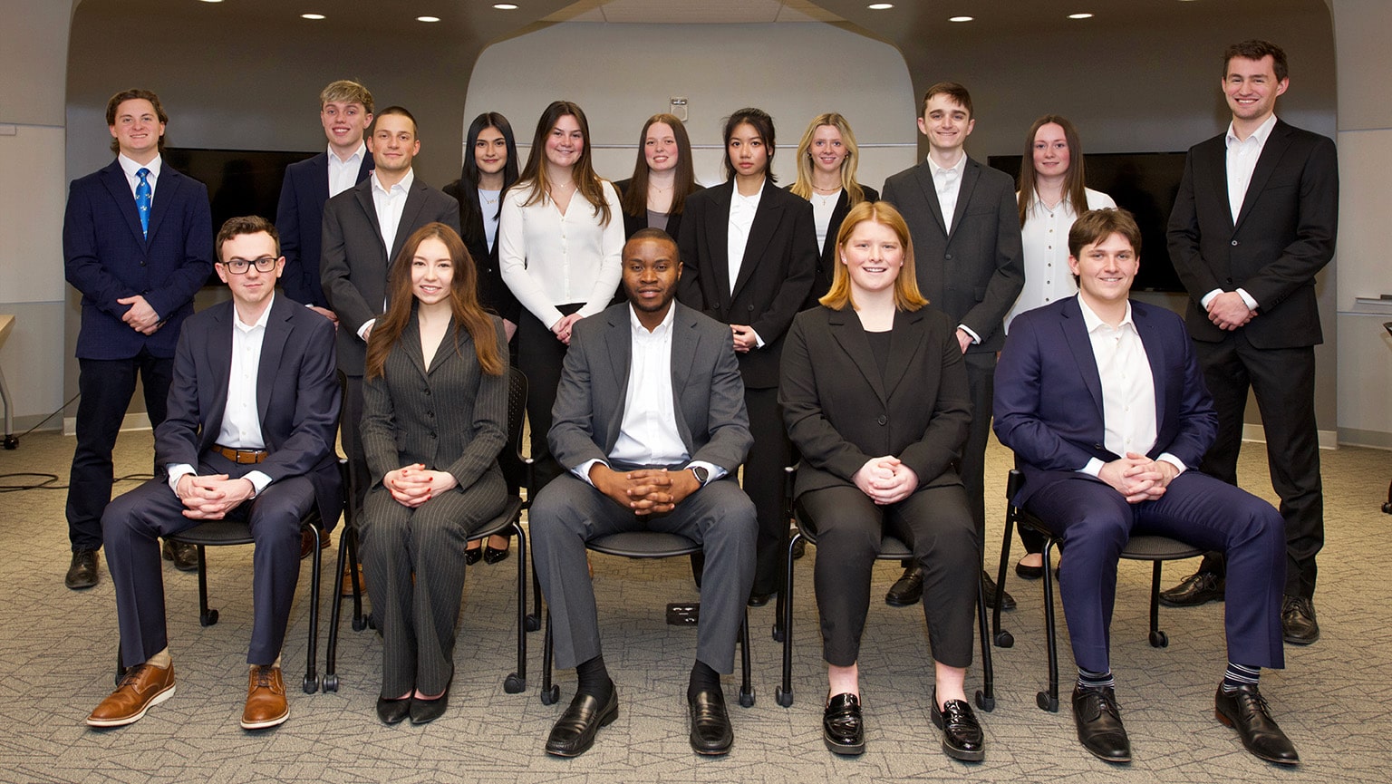 Business students, dressed in suits, posing for a group photo of the combined StartUp teams.