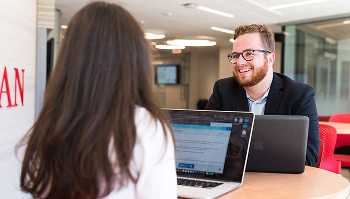 Grad students collaborating at a study room table in the state-of-the-art Dolan building.