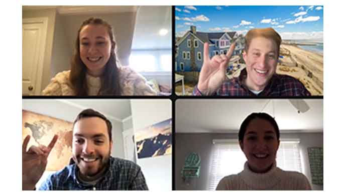 Four individuals engaged in a video call, with one person prominently displaying a "Stags Up"  sign gesture