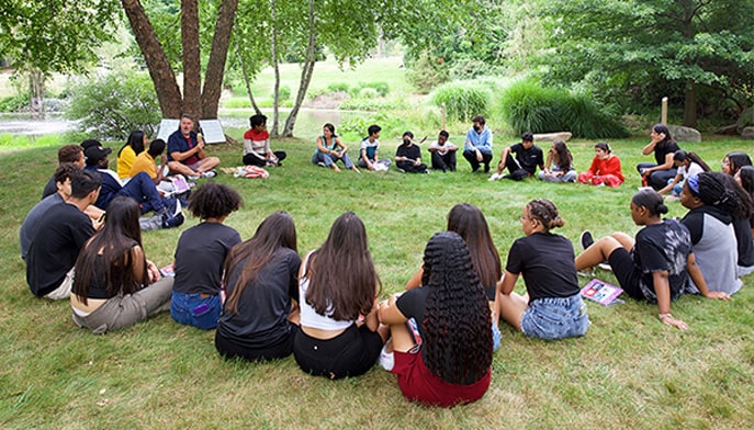 Writing students gather on campus lawn.