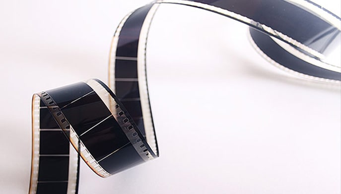 A roll of film spiraling open on a white table.