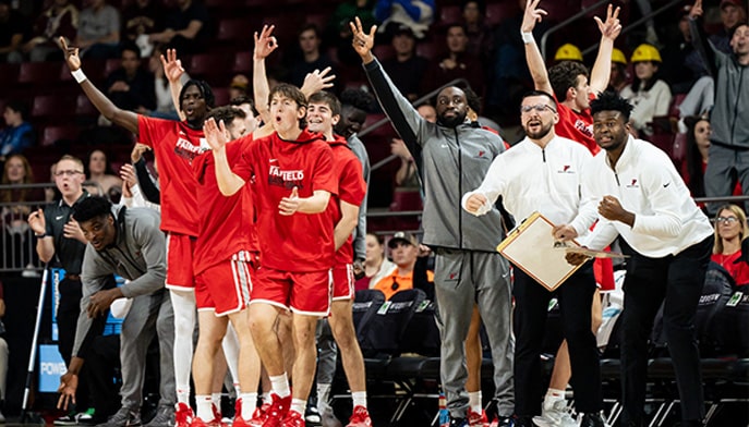 Men's basketball players and coaches cheering on sideline