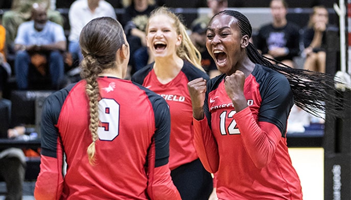 Fairfield volleyball players celebrate on court.