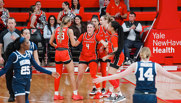 Celebrating on the court, Fairfield University's women's basketball team expresses joy and unity after a hard-fought victory.