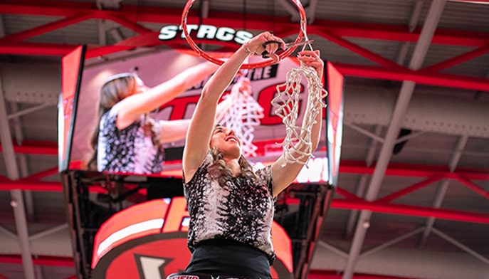 Coach Carly cuts down the nets at Mahoney Arena.