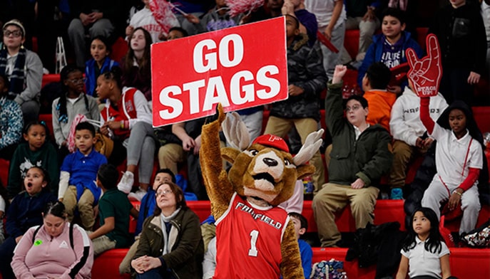 Lucas the Stag at Kids' Day Out 2023 holding a red sign with one arm over his head that reads: Go Stags.