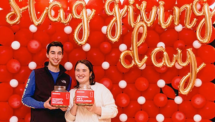 Two students standing side by side holding signs up advocating for StaGiving Day.