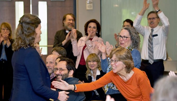 College of Arts and Sciences faculty standing and celebrating during awards ceremony.