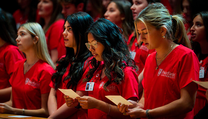 Nursing students in Fairfield-red scrubs at their clinical initiation ceremony, reciting their new code of conduct as a cohort.