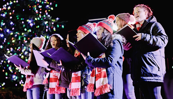 Fairfield students singing Christmas carols outside, near the campus holiday tree.