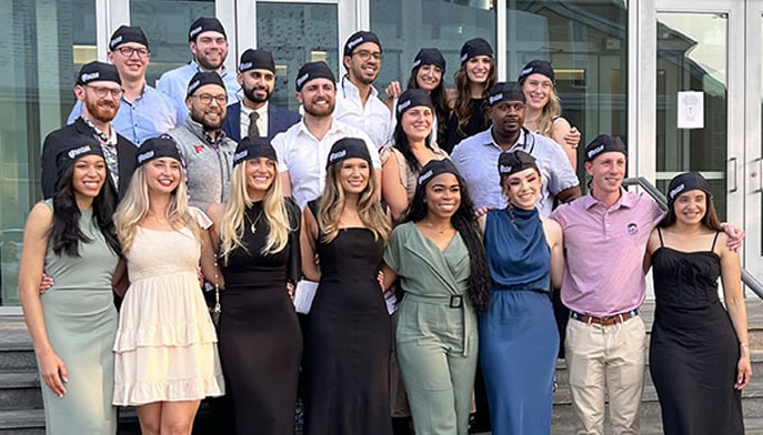 Image of residents pose in their surgical caps after ceremony