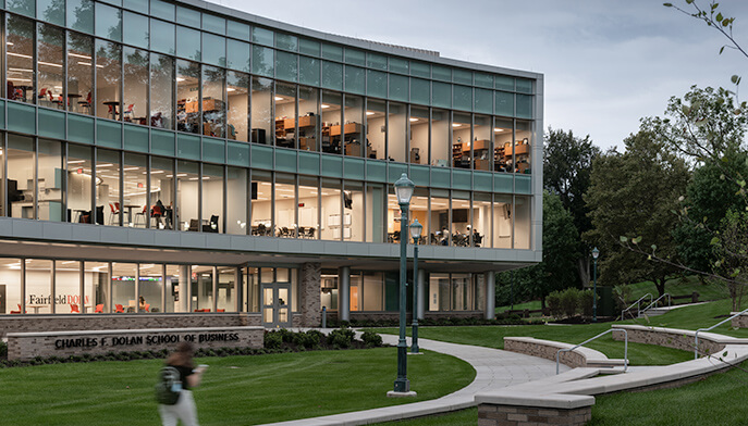 A modern building featuring a large glass wall, surrounded by a lush grassy area, reflecting contemporary architecture.