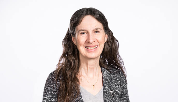 Dr. Joan L. Lee wearing a gray shirt, standing confidently with a neutral background.