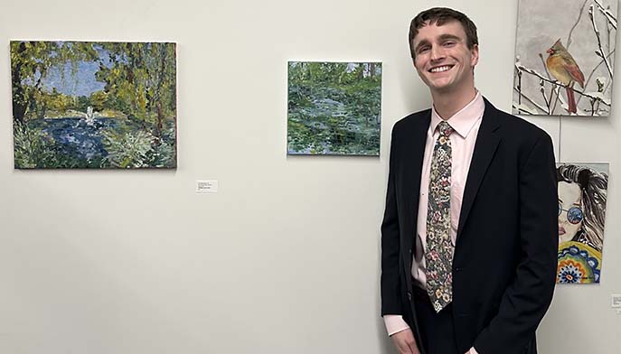 Student standing in front of artwork. 