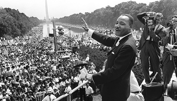 Historical, archival photo of Martin Luther King Jr. waving to the crowd before his speech.